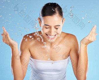 水飞溅护肤品女人孤立的蓝色的背景美化妆品清洁快乐微笑人模型洗脸皮肤病学面部健康审美工作室