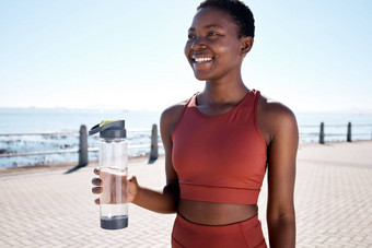 健身水黑色的女人跑步者海滩培训健康有氧运动海洋微笑快乐锻炼喝水女人放松运行锻炼走水合作用