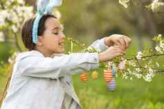 可爱的女孩兔子耳朵盛开的树分支在户外春天一天孩子有趣的复活节蛋亨特花园
