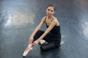 亚洲女人穿着黑色的紧身衣裤紧身裤尖端鞋子坐在地板上