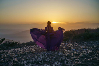 日落紫色的衣服女人山上升神秘的日落云女孩长紫色的衣服草地草梦想紫色的花