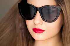 美时尚风格脸肖像美丽的女人穿时尚的猫眼睛太阳镜红色的口红化妆奢侈品附件夏天生活方式魅力别致的