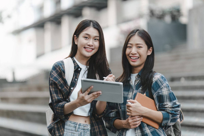 年轻的亚洲女人大学学生朋友在户外大学学生