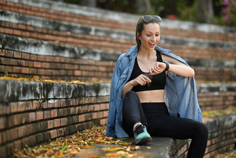 拍摄快乐浅黑肤色的女人运动女人穿着运动服装检查健身结果<strong>智能手表</strong>