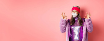 科维德流感大流行时尚概念很酷的亚洲祖母穿时尚的迪斯科衣服呼吸器显示迹象穿脸面具社会距离粉红色的背景