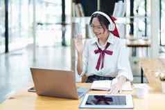 肖像十几岁的亚洲女人电脑穿耳机笔记本研究在线视频会议木桌子上图书馆
