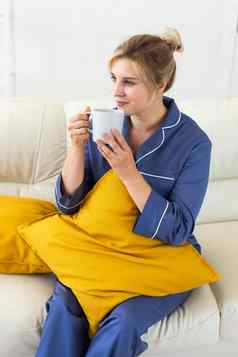 微笑金发女郎女人坐着舒适的教练生活房间睡衣饮料茶咖啡家居服免费的时间假期首页概念