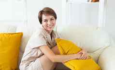 微笑女人坐着舒适的couich生活房间睡衣家居服免费的时间假期首页概念