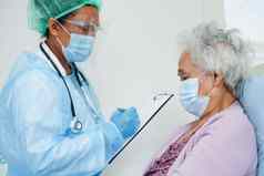 医生检查亚洲老高级女人病人穿面具保护科维德冠状病毒