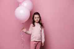 可爱的女孩粉红色的衣服持有群粉红色的柔和的氦气球孤立的粉红色的颜色背景