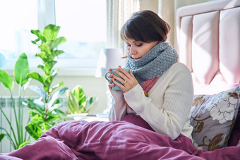 女人坐着床上毯子气候变暖围巾热喝杯子