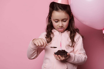 可爱的婴儿女孩品尝生日蛋糕摆姿势充<strong>气节</strong>日粉红色的柔和的气球粉红色的背景