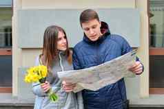 年轻的夫妇旅行者冬天城市男人。女人阅读地图