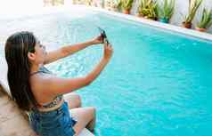 女孩假期边缘游泳池采取自拍有吸引力的女孩假期游泳池采取自拍
