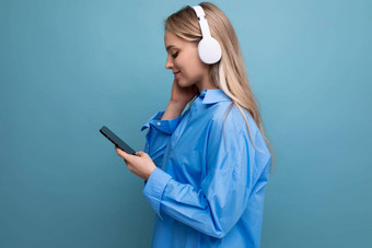 明亮的可爱的女孩无线大耳机电话手听快乐音乐播放列表蓝色的背景