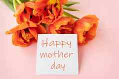 美丽的花束橙色牡丹郁金香白色卡中间单词快乐妈妈。一天粉红色的背景
