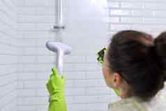 女人清洁浴室洗玻璃淋浴蒸汽