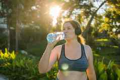 超重女人喝水慢跑公园肖像年轻的大号渴了女人瓶水在户外复制空间体育医疗保健重量失去健身幸福概念
