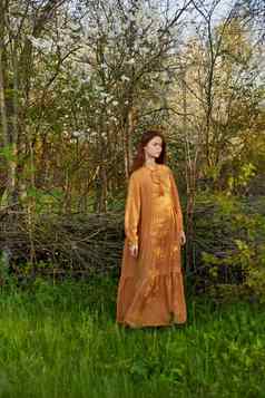 优雅的复杂的女人提出了放松站柳条栅栏别墅长橙色衣服一边垂直摄影自然