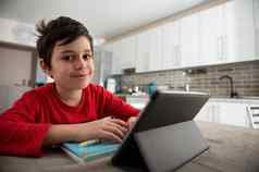 小学学校学生男孩距离学习微笑相机看网络研讨会数字平板电脑