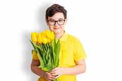 快乐男孩黄色的t恤持有花束黄色的郁金香站白色背景