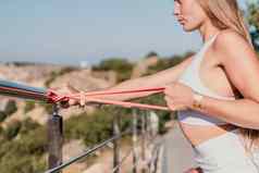 健身女人海户外锻炼健身橡胶乐队公园海滩女健身瑜伽例程概念健康的生活方式快乐适合女人锻炼橡胶乐队公园