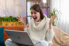 惊讶年轻的女人移动PC电脑收到好新闻消息震惊了胜利庆祝赢得