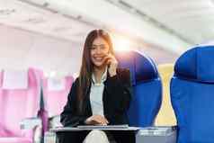 美丽的亚洲业务女人聊天客户端移动电话飞行工作旅行业务概念