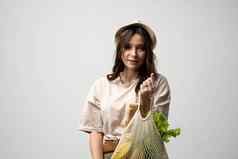 女孩持有网购物袋蔬菜绿色塑料袋浪费塑料免费的生态友好的概念可持续发展的生活方式