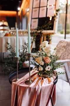 节日装饰细节白色长蜡烛黄金烛台花作文白色黄色的粉红色的花绿色植物黑色的金属表格粉红色的桌布婚礼装饰