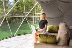 女人工作移动PC地理圆顶帐篷绿色蓝色的背景舒适的野营豪华露营假期假期生活方式概念在户外小屋风景优美的背景