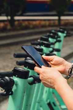 女手移动电话扫描代码电踏板车街e-scooter租赁服务应用程序替代运输城市生态友好的