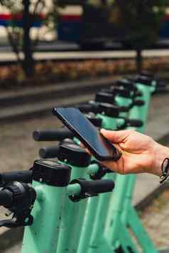 女手移动电话扫描代码电踏板车街e-scooter租赁服务应用程序替代运输城市生态友好的