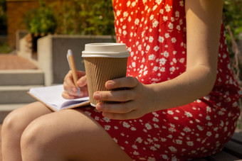 认不出来年轻的女人红色的衣服喝咖啡工艺纸杯写作感激之情<strong>杂志</strong>木板凳上今天感激的发现<strong>杂志</strong>反射有创意的写作增长个人发展概念护理幸福精神上的健康