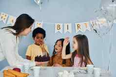 女人持有蛋糕孩子们庆祝生日聚会，派对在室内有趣的