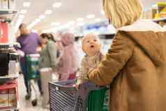 不拘礼节地穿着妈妈。选择产品部门超市杂货店商店婴儿婴儿男孩孩子购物车