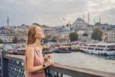 年轻的旅游女人加拉塔桥金角湾伊斯坦布尔全景城市景观著名的旅游目的地横跨博斯普鲁斯海峡海峡通道旅行景观博斯普鲁斯海峡火鸡欧洲亚洲