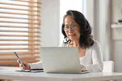 积极的中间岁的女人看培训类在线网络研讨会移动PC电脑舒适的首页