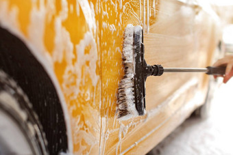 黄色的车洗服务洗车细节刷清洁一边覆盖洗发水泡沫
