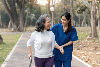 护士帮助上了年纪的女人沃克护士持有手上了年纪的女人走公园设施