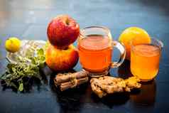 特写镜头Herbal有机汁苹果橙色汁肉桂棒柠檬汁姜阿德拉克坦蒂叶子神圣的罗勒叶子透明的玻璃生成分