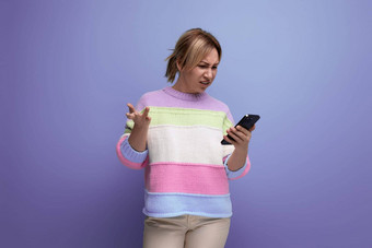 金发碧眼的女孩使购买互联网持有智能手机手紫色的背景