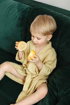 肖像男孩黄色的浴袍坐在绿色沙发谎言一半橙色