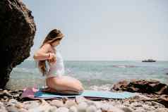 女人海健身快乐女人长头发健身教练白色比基尼伸展运动普拉提瑜伽席海女健身瑜伽例程概念健康的生活方式