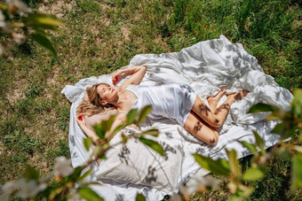 女人睡觉白色床上<strong>新</strong>鲜的春天草花园穿着蓝色的睡衣