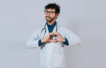 英俊的医生使心手势手快乐医生指出手指年轻的医生使心形状孤立的