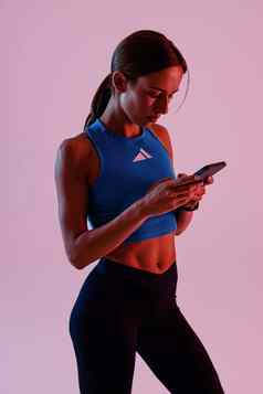 运动女人服装锻炼持有智能手机站工作室背景