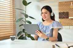 有吸引力的女人穿无线耳机检查社会媒体工作在线数字平板电脑
