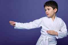 合气道摔跤手欧洲年男孩白色和服提高了战斗技能孤立的紫色的背景复制空间东方武术艺术