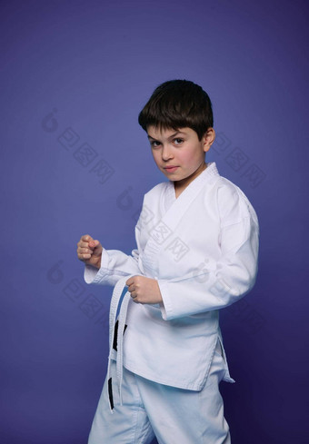 肖像英俊的高加索人十几岁的男孩合气道摔跤手练习武术技能紫色的墙背景东方武术艺术概念